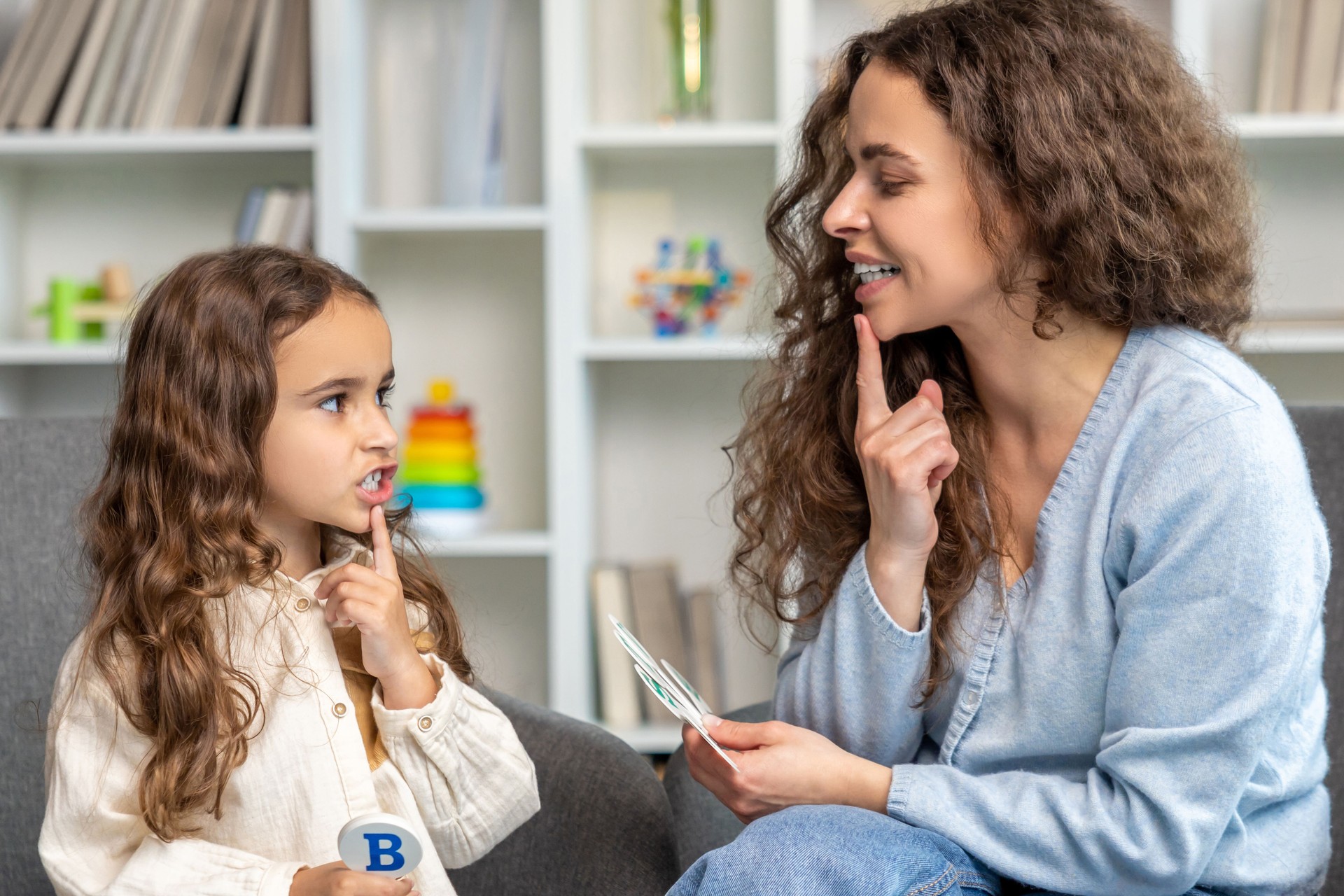 Cute long-haired girl having speech therapy session with the doctor
